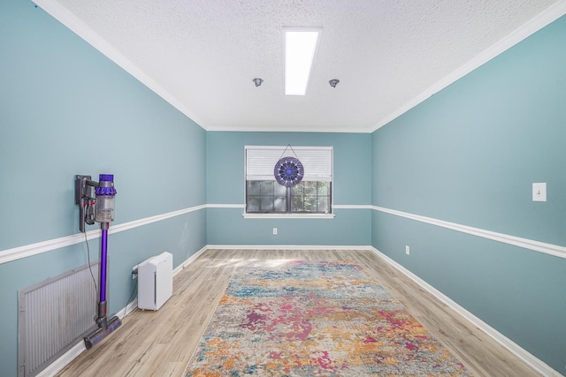 unfurnished room featuring a textured ceiling, light hardwood / wood-style floors, and ornamental molding