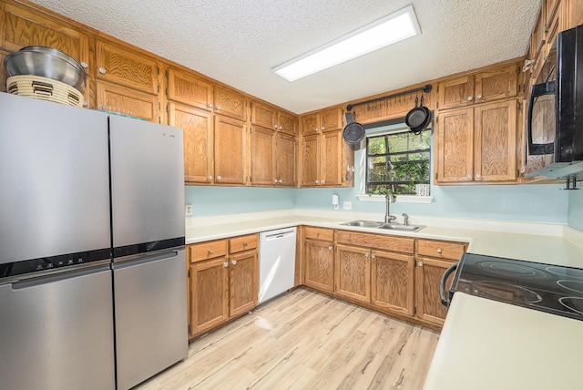 kitchen featuring stainless steel fridge, a textured ceiling, white dishwasher, sink, and light hardwood / wood-style flooring