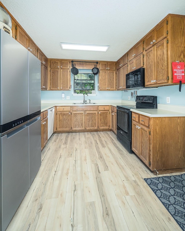 kitchen featuring light wood-type flooring, sink, and black appliances