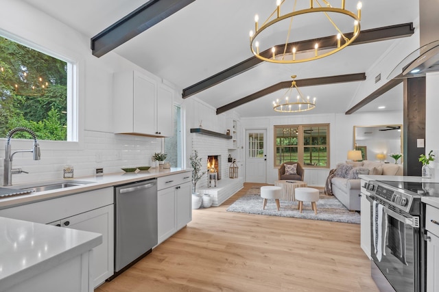 3744 Lifford Cir, Tallahassee, FL 32309 - kitchen featuring stainless steel appliances, a chandelier, open floor plan, a fireplace, and white cabinetry