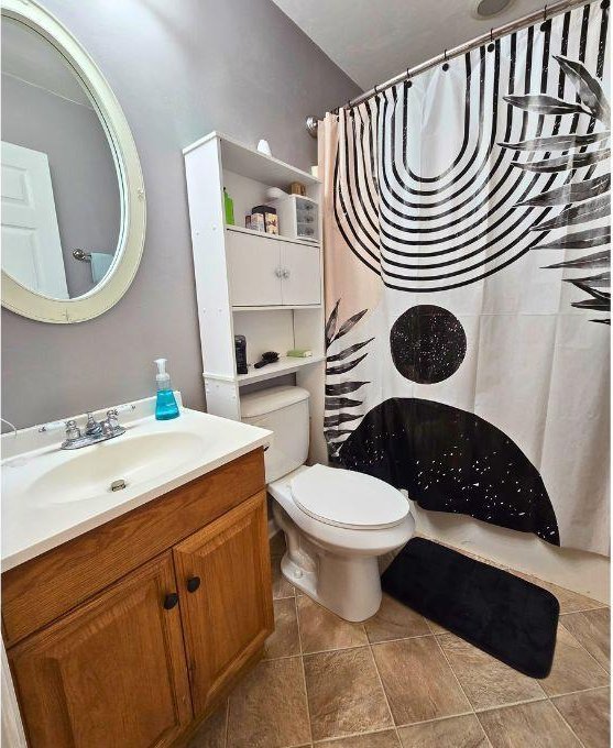 bathroom with walk in shower, vanity, and toilet