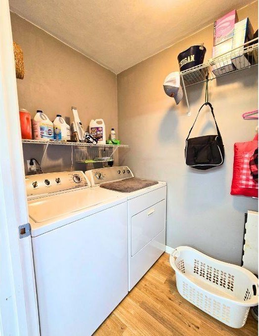 laundry area featuring washing machine and clothes dryer and light wood-type flooring