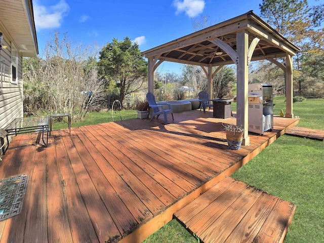 wooden terrace featuring a gazebo, a yard, and a hot tub