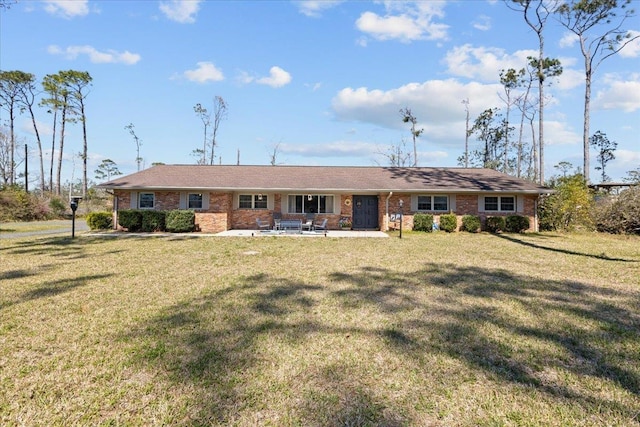 ranch-style home featuring a front yard, brick siding, and a patio