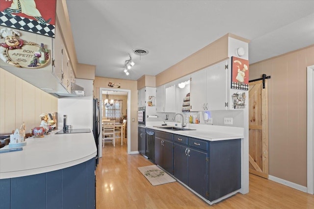 kitchen featuring blue cabinetry, a barn door, light wood-style floors, and a sink