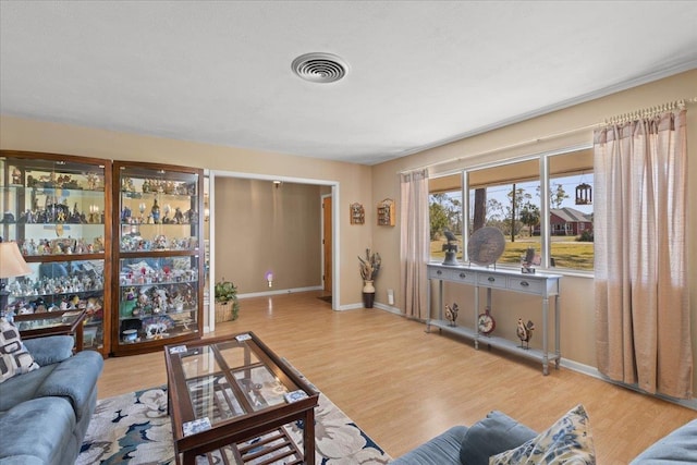 living room with visible vents, baseboards, and wood finished floors