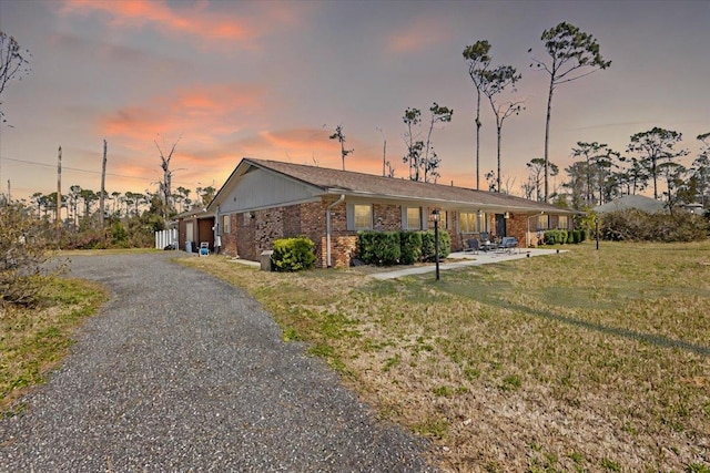 view of front of house featuring driveway, a front yard, and brick siding