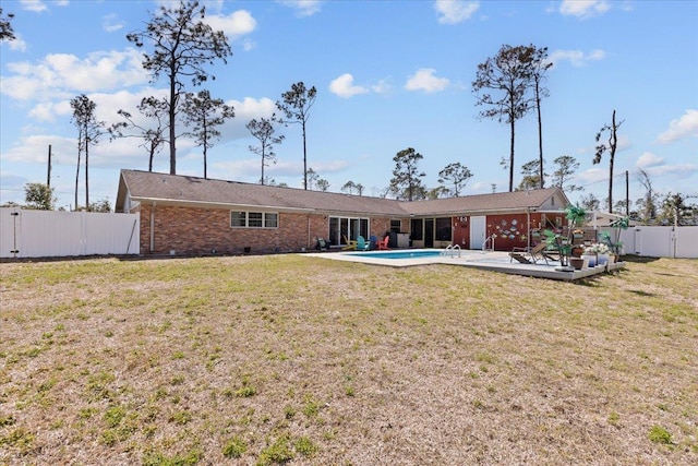 back of property featuring a patio, a fenced backyard, brick siding, crawl space, and a lawn