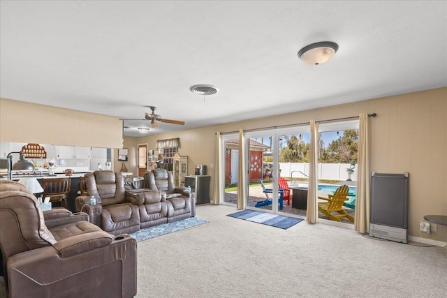 living room featuring a ceiling fan, visible vents, and light carpet