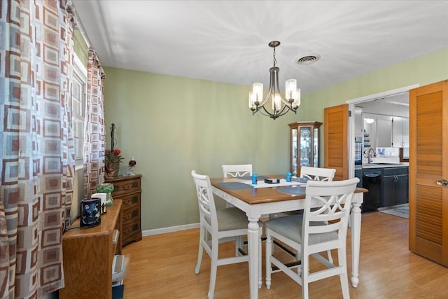 dining space with light wood finished floors, baseboards, visible vents, and an inviting chandelier