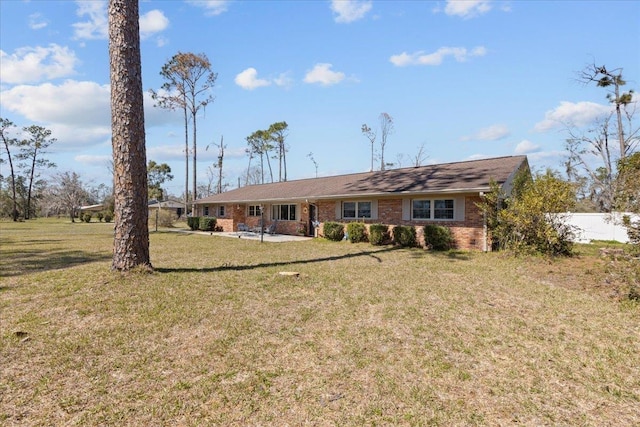 rear view of house featuring fence, a lawn, and brick siding