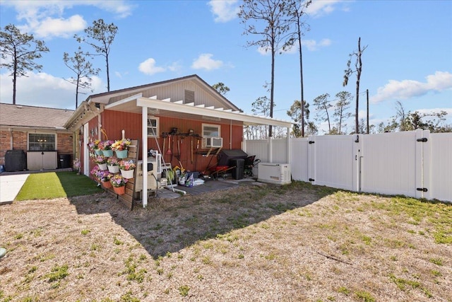 back of property with a yard, cooling unit, a gate, and fence