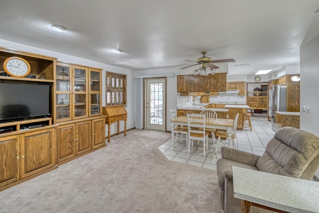 living room with ceiling fan, light colored carpet, and a textured ceiling