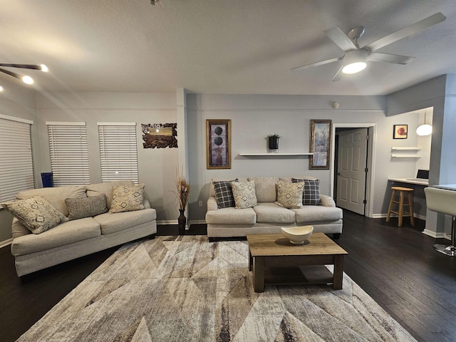 living area featuring dark wood-style floors, a ceiling fan, and baseboards