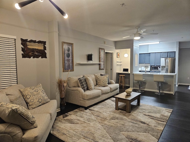 living room featuring a ceiling fan, dark wood-type flooring, and baseboards