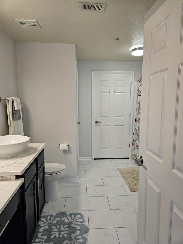 bathroom featuring a textured ceiling, marble finish floor, vanity, and visible vents