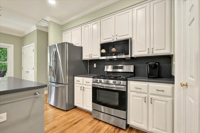 9078 Shoal Creek Dr, Tallahassee, FL 32312 - kitchen featuring stainless steel appliances, dark countertops, crown molding, light wood-style flooring, and white cabinetry