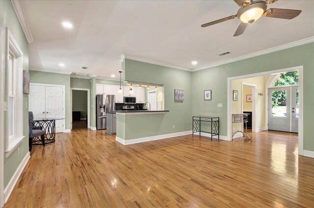 9078 Shoal Creek Dr, Tallahassee, FL 32312 - kitchen featuring stainless steel appliances, light wood-style flooring, white cabinets, crown molding, and a peninsula