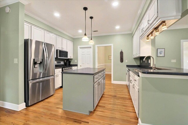 9078 Shoal Creek Dr, Tallahassee, FL 32312 - kitchen with appliances with stainless steel finishes, dark countertops, a center island, ornamental molding, and light wood-type flooring