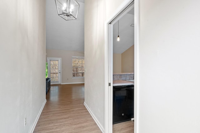 corridor featuring vaulted ceiling, a chandelier, and light hardwood / wood-style floors