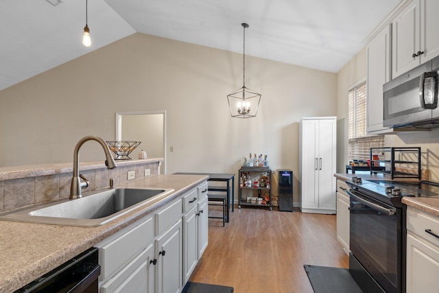 kitchen with pendant lighting, white cabinetry, sink, black appliances, and light hardwood / wood-style flooring