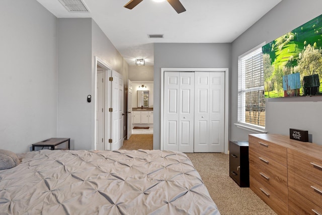 carpeted bedroom with a closet, ceiling fan, and ensuite bathroom