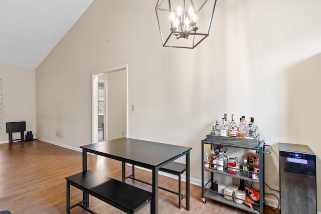 dining room featuring an inviting chandelier, high vaulted ceiling, and hardwood / wood-style floors