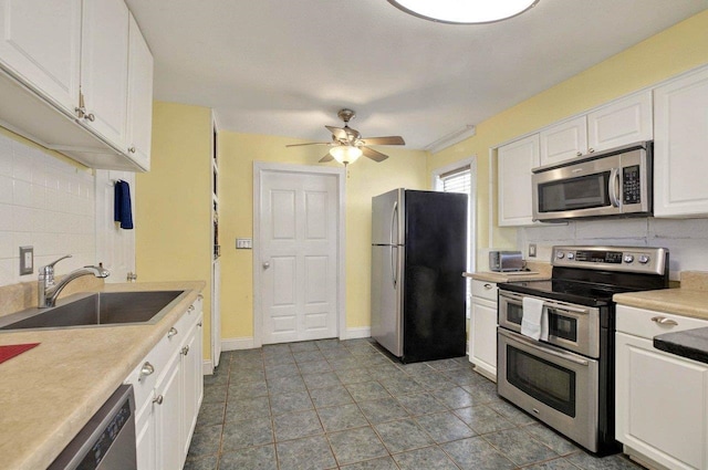 1195 Alligator Dr, Alligator Point, FL 32346 - kitchen featuring stainless steel appliances, a sink, decorative backsplash, ceiling fan, and white cabinets