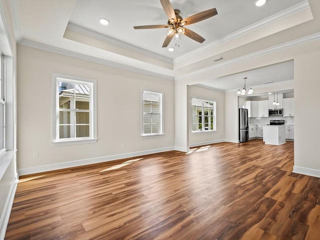 unfurnished living room featuring dark wood-type flooring, ceiling fan with notable chandelier, a raised ceiling, and crown molding