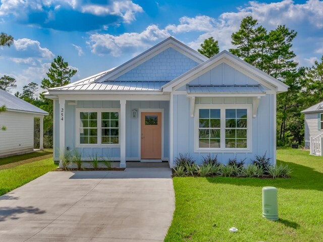 254 Ante Beppum Loop, Carrabelle, FL 32322 - view of front of house with board and batten siding, a front yard, a standing seam roof, covered porch, and a metal roof