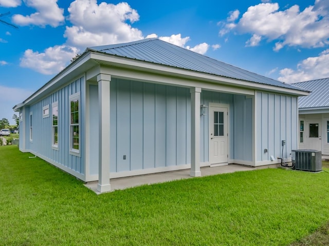 back of property featuring central air condition unit and a yard