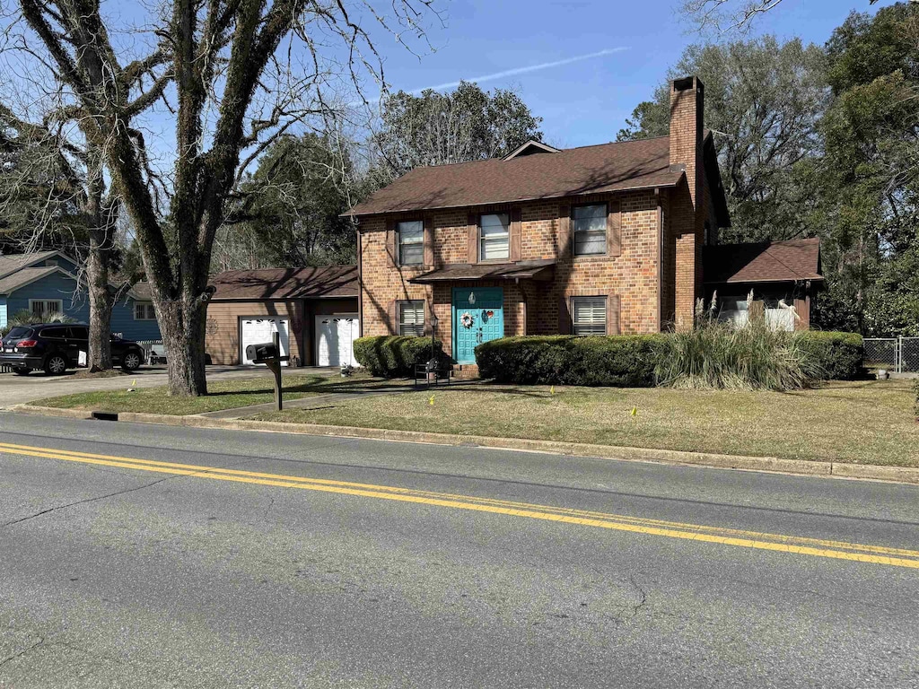 view of front of property featuring brick siding, a chimney, and a front lawn