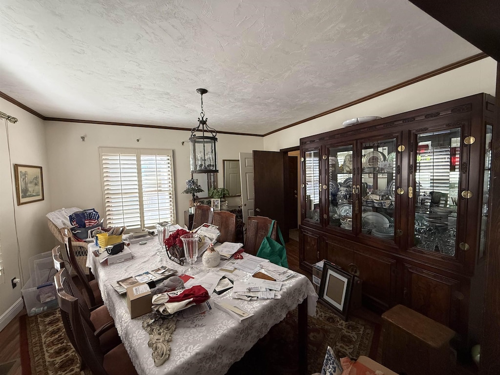 dining room featuring a textured ceiling, ornamental molding, and baseboards