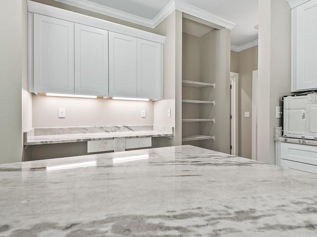 kitchen featuring white cabinets, light stone countertops, and ornamental molding