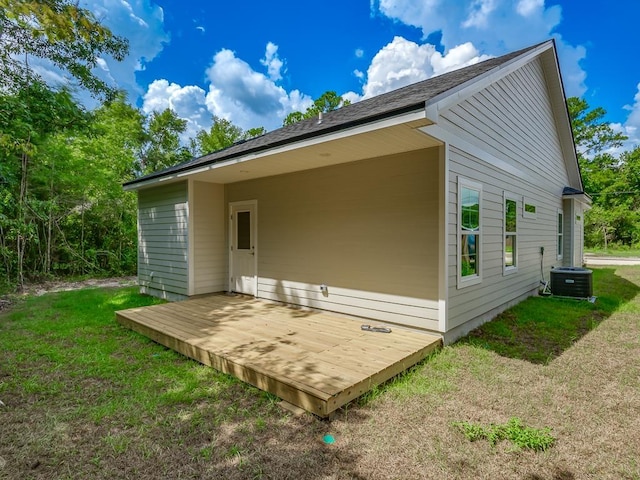 rear view of property with a lawn, cooling unit, and a deck