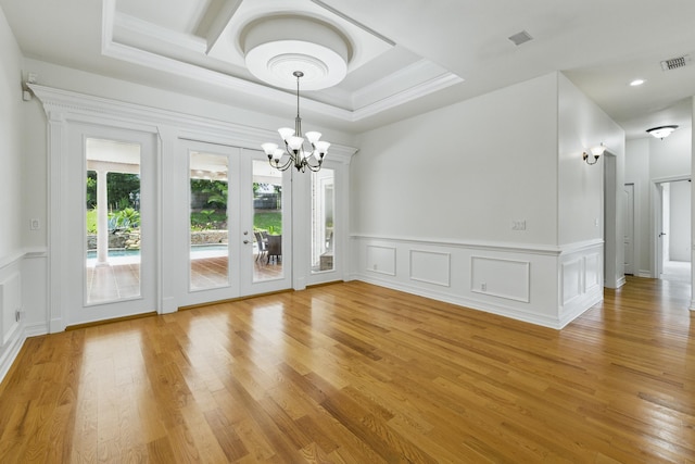 9227 Shoal Creek Dr, Tallahassee, FL 32312 - empty room featuring a chandelier, light wood-style flooring, a decorative wall, french doors, and ornamental molding