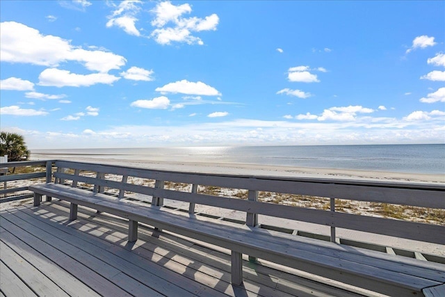 wooden deck with a water view and a beach view