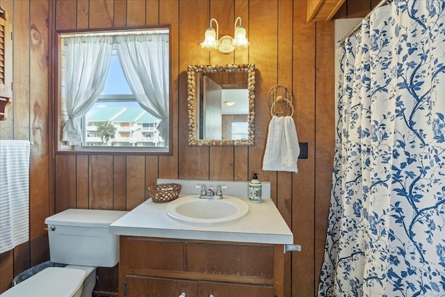 bathroom featuring vanity, a shower with shower curtain, toilet, and wood walls