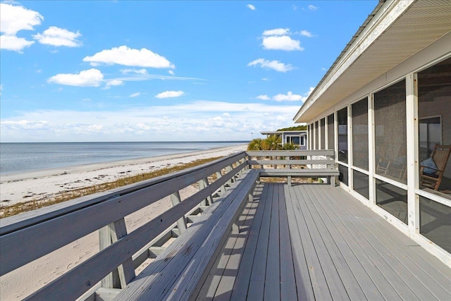 deck featuring a water view, a beach view, and a sunroom