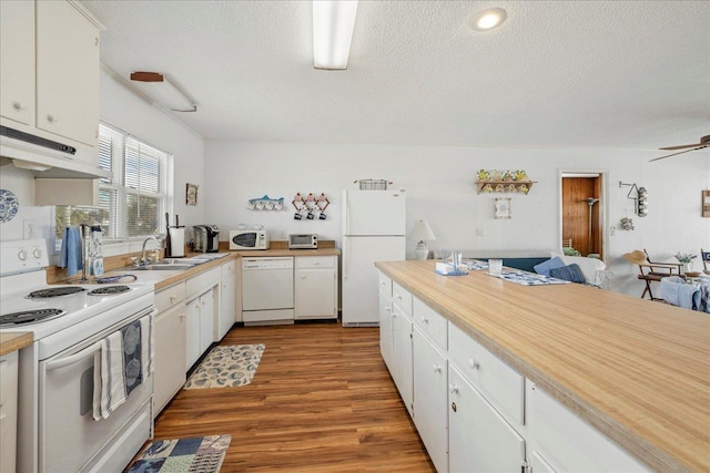 kitchen featuring hardwood / wood-style floors, white cabinetry, sink, white appliances, and a textured ceiling