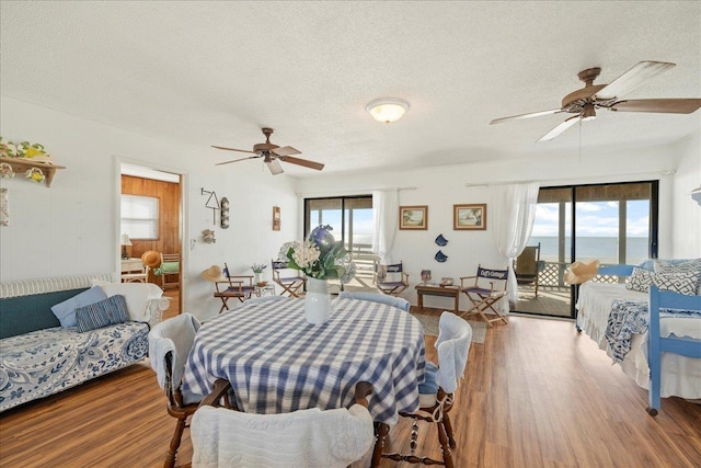 dining area featuring a textured ceiling, plenty of natural light, wood-type flooring, and a water view