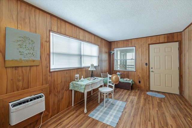 interior space featuring a wall unit AC, wooden walls, hardwood / wood-style floors, and a textured ceiling