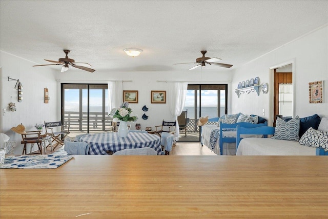 living room with wood-type flooring, a water view, a textured ceiling, and ceiling fan