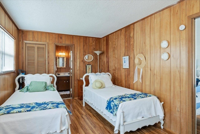 bedroom with crown molding, dark hardwood / wood-style flooring, a textured ceiling, and wood walls