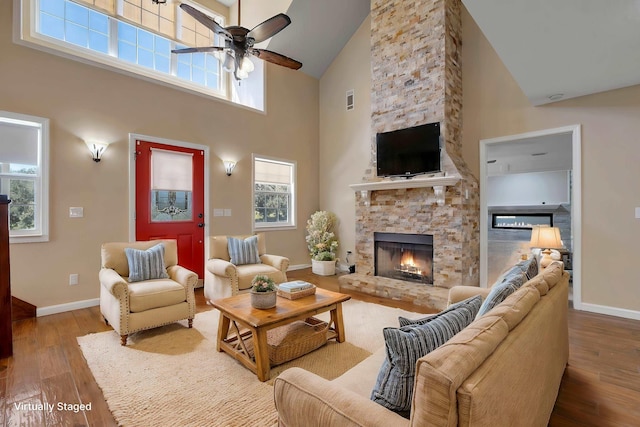 living area featuring a ceiling fan, a fireplace, baseboards, and wood finished floors