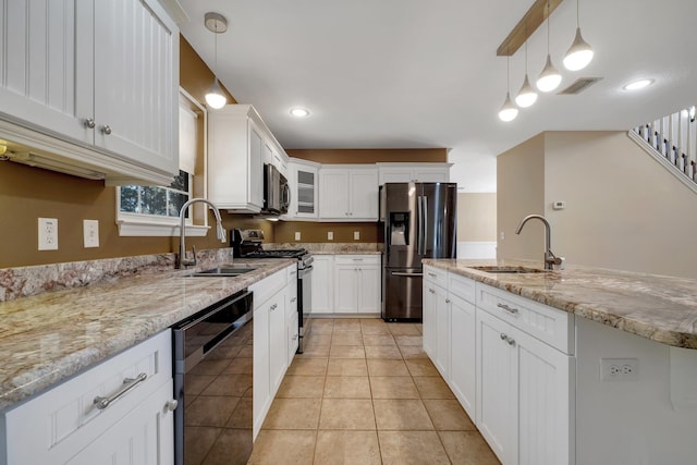 kitchen featuring white cabinets, stainless steel appliances, a sink, and decorative light fixtures