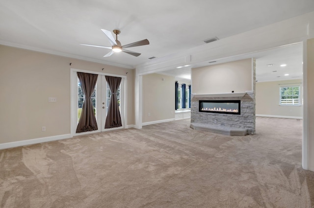 unfurnished living room with a stone fireplace, ornamental molding, visible vents, and light colored carpet