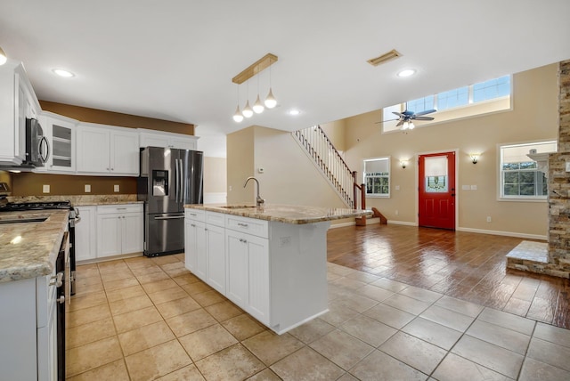 kitchen featuring stainless steel appliances, glass insert cabinets, a kitchen island with sink, and white cabinets