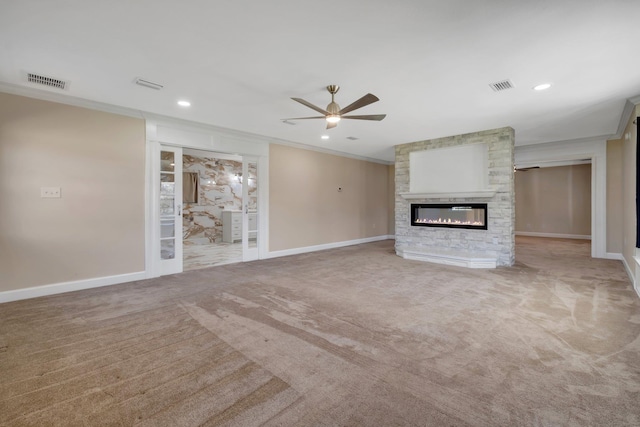 unfurnished living room featuring light colored carpet, a large fireplace, visible vents, and crown molding