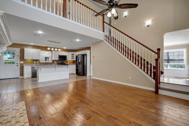 unfurnished living room featuring light wood-style floors, baseboards, and stairs